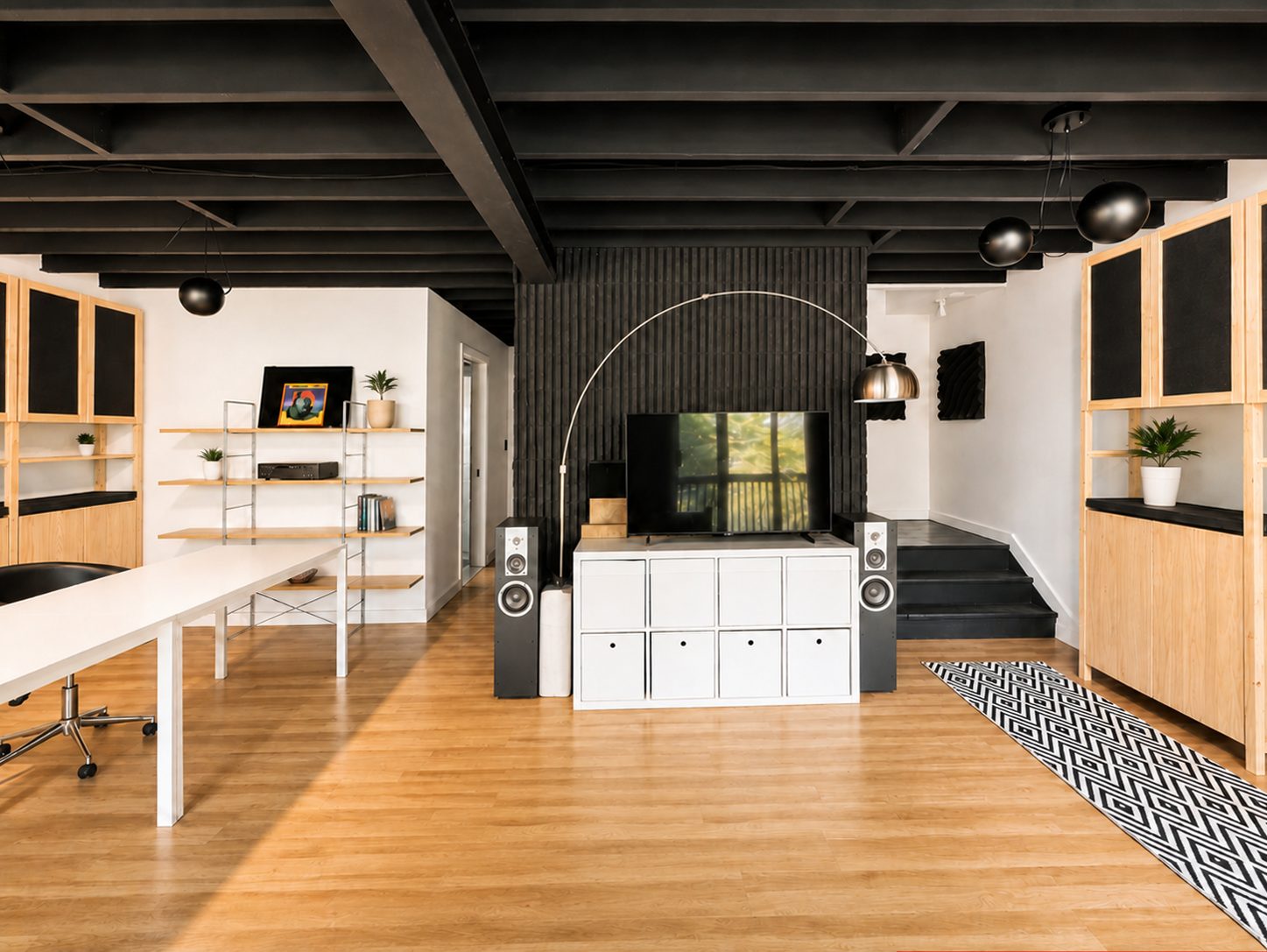 Lower lounge with TV, speakers, shelving and long white desk