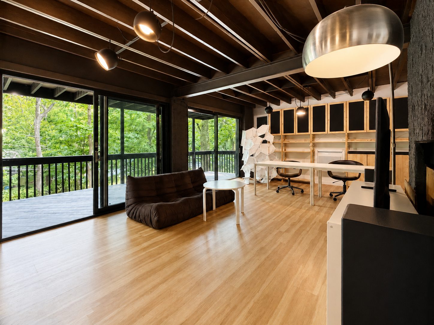 Basement lounge with sofa, long desk and glass doors to the deck