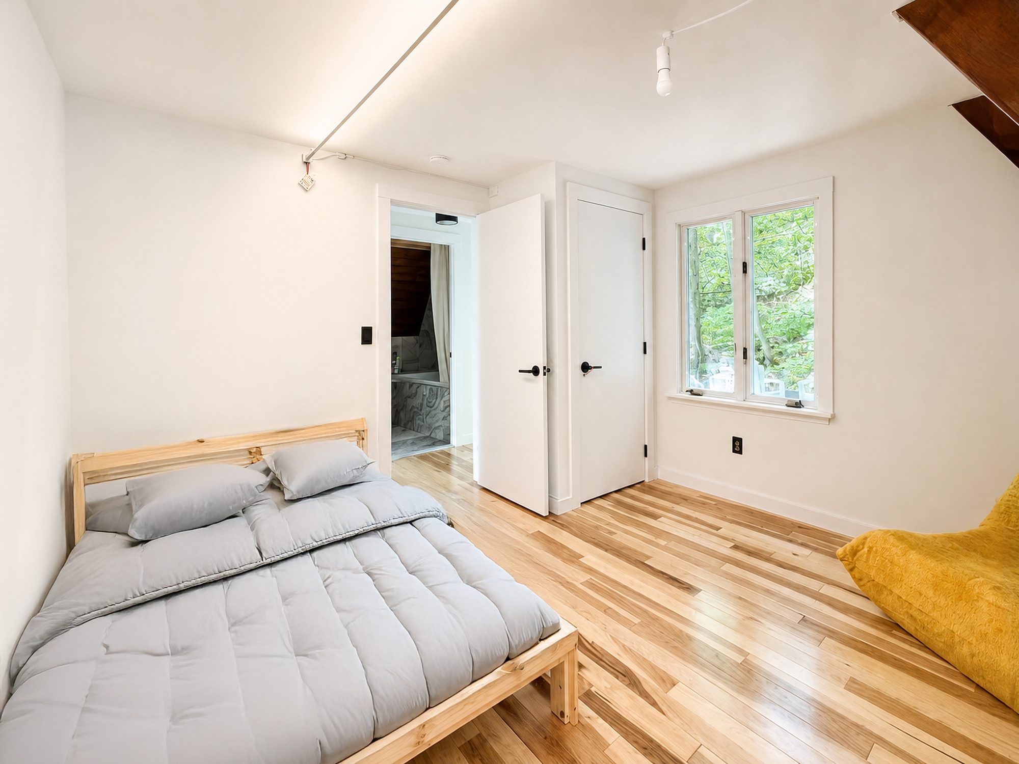 Bright bedroom with double bed and yellow lounge chair