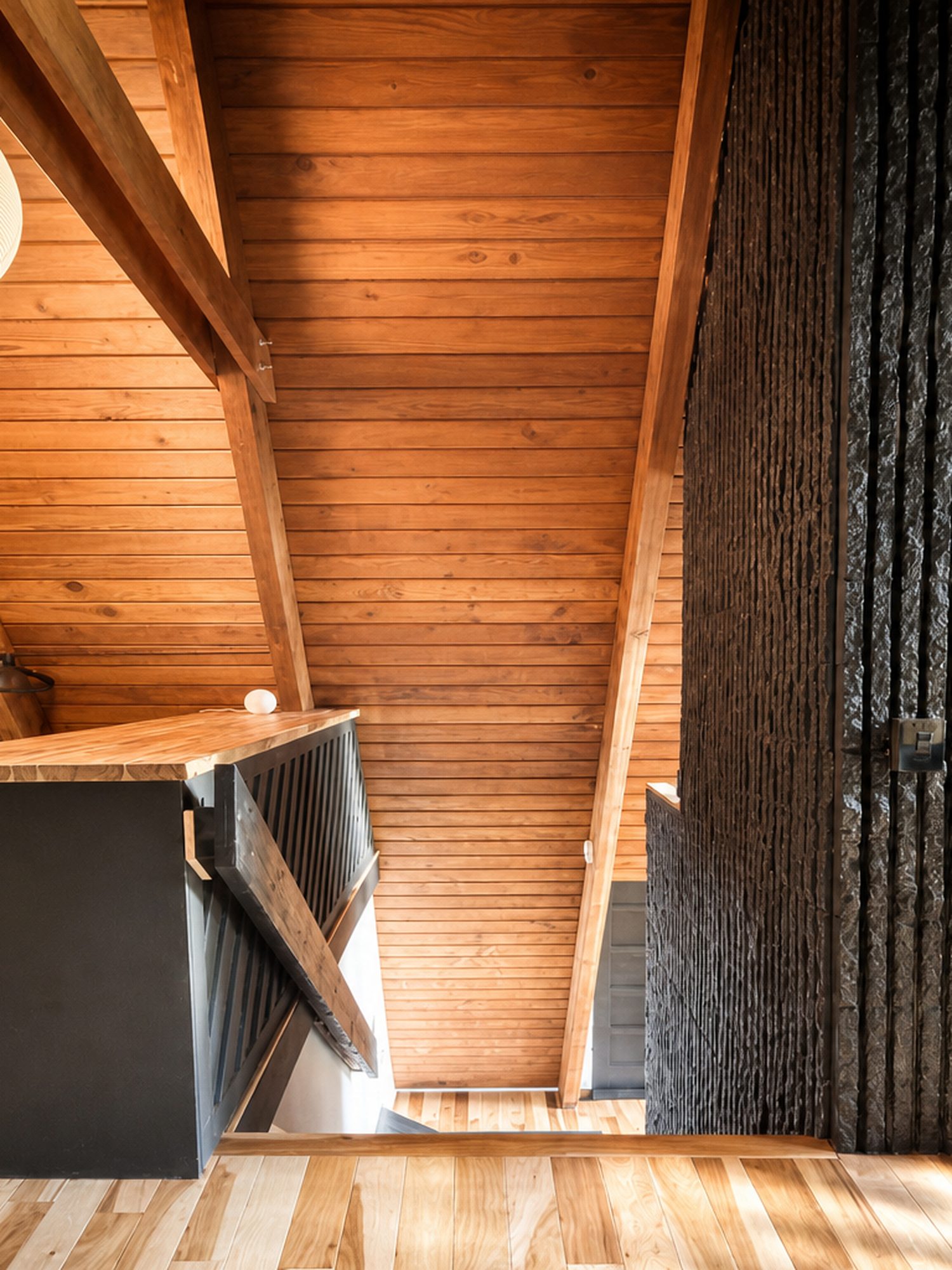 Looking up the stair at cedar ceilings and black railings