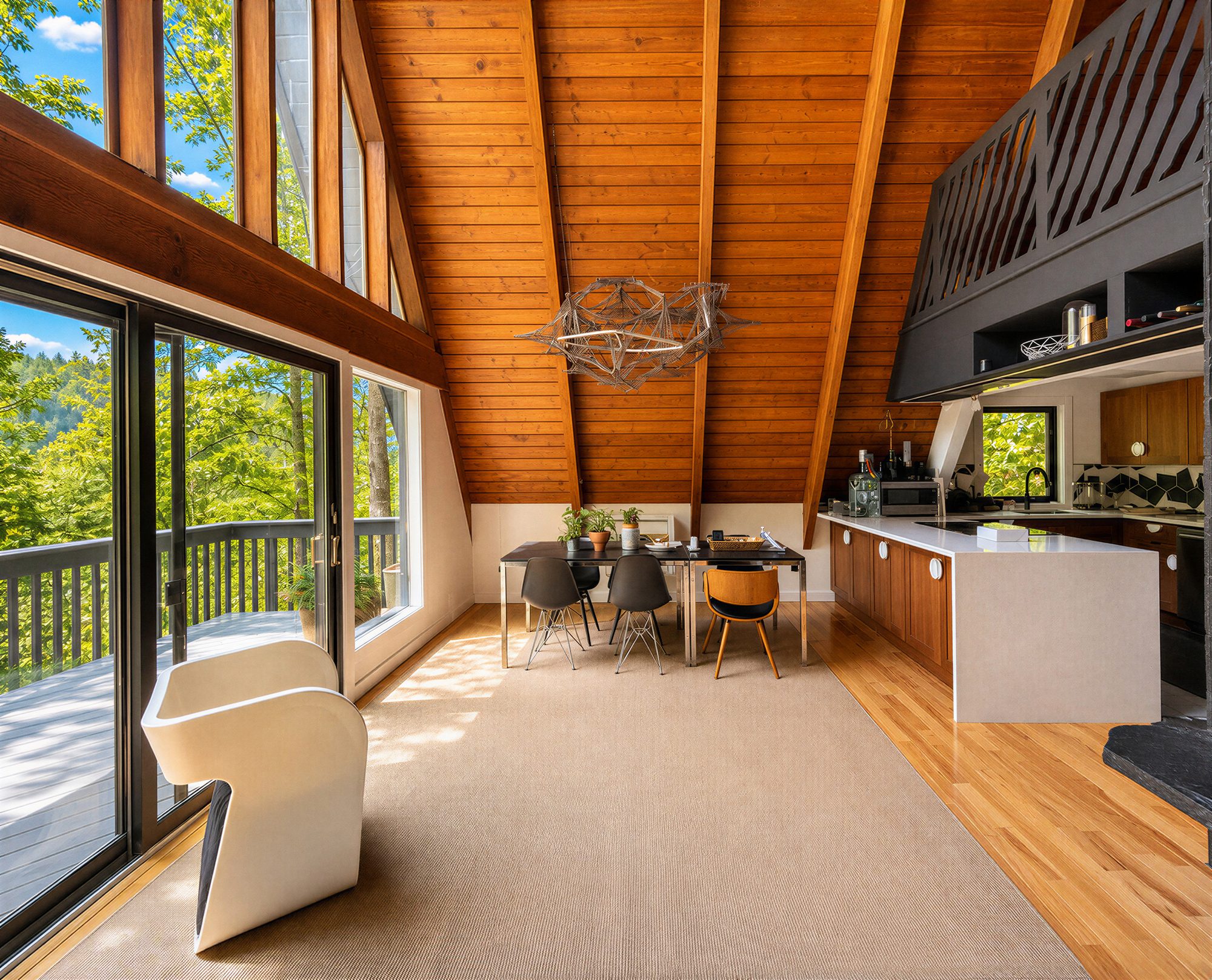 Wide view of the A-frame living and dining space with wall of glass to the deck