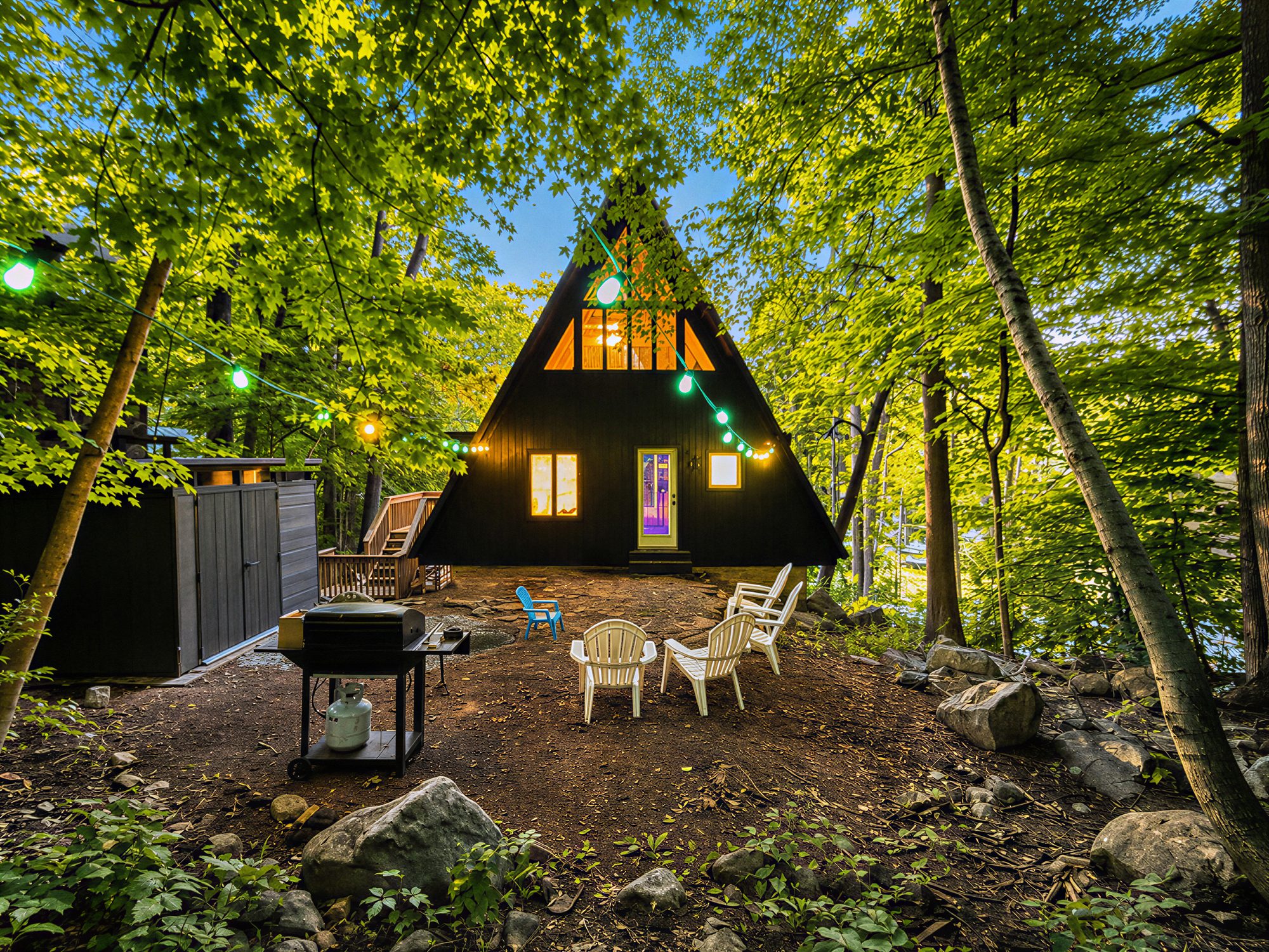 The A-frame at dusk from the backyard with chairs and string lights